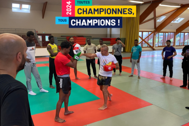 Deux participants participent à un combat de Muay Thaï, entourées par d'autres participants